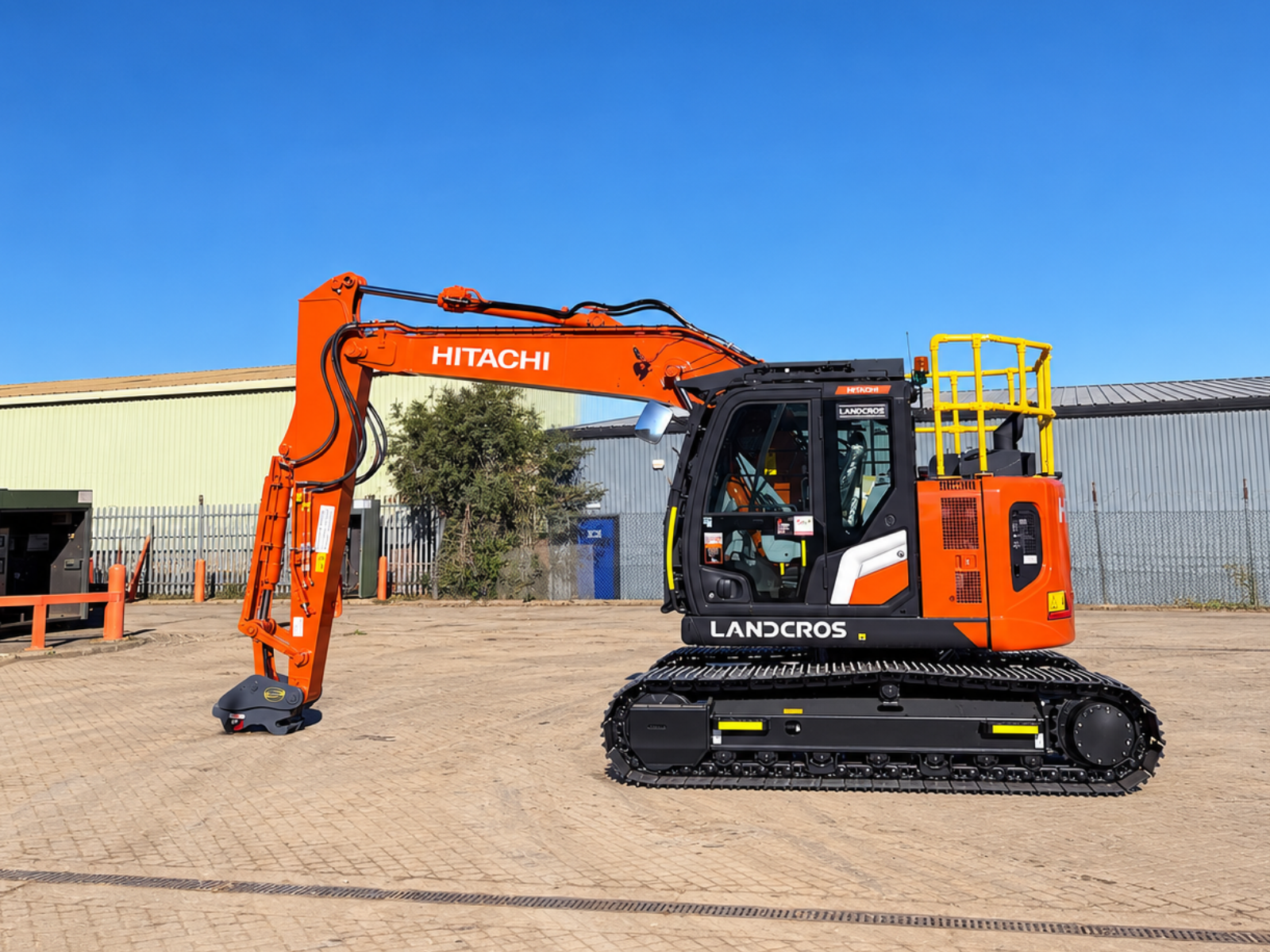 Hitachi excavator in side profile parked in a depot yard, with UK safety handrails and newly cleaned tracks