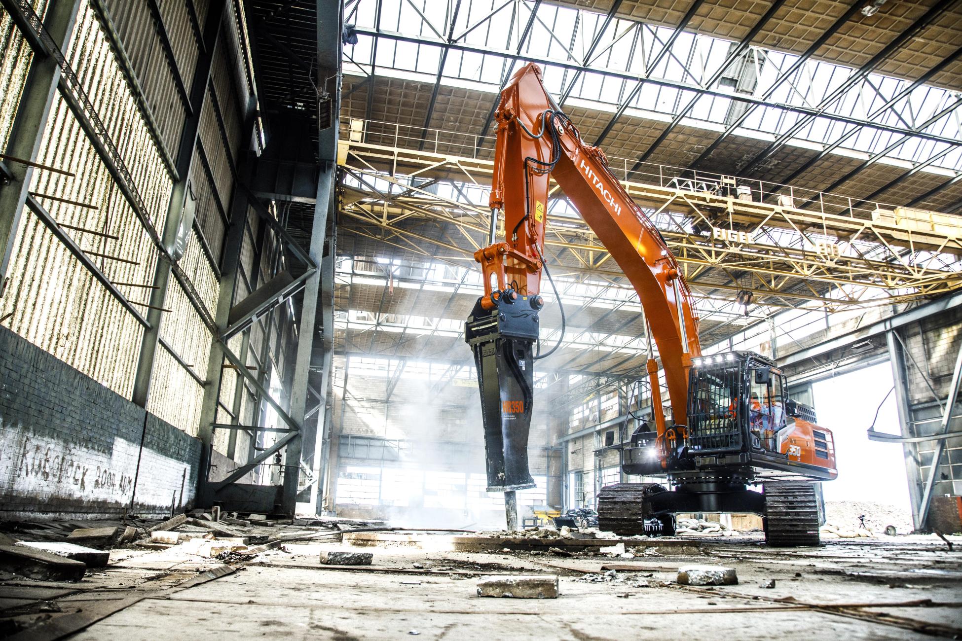 Hitachi excavator fitted with a hydraulic breaker working inside an industrial building