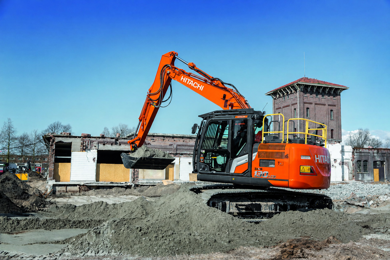 Hitachi ZX130LCN excavator with yellow safety handrails working on a demolition site.