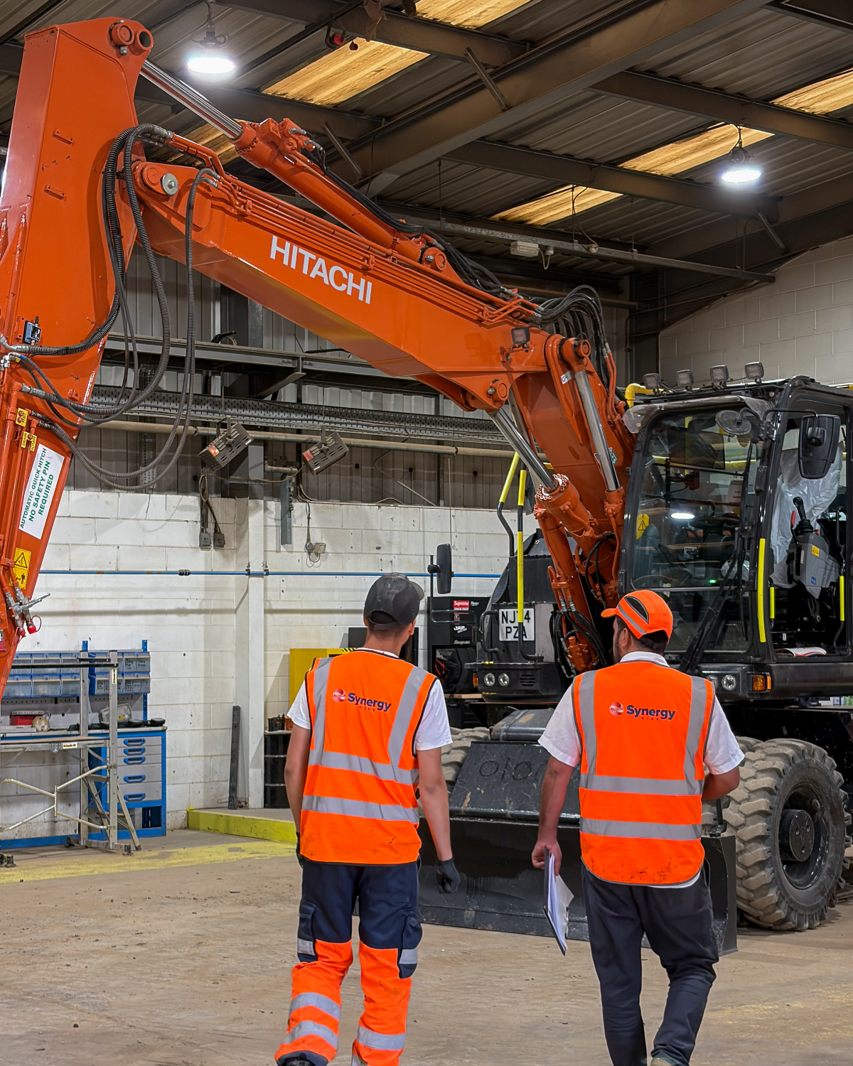 Synergy Hire team supporting a Hitachi excavator in the workshop
