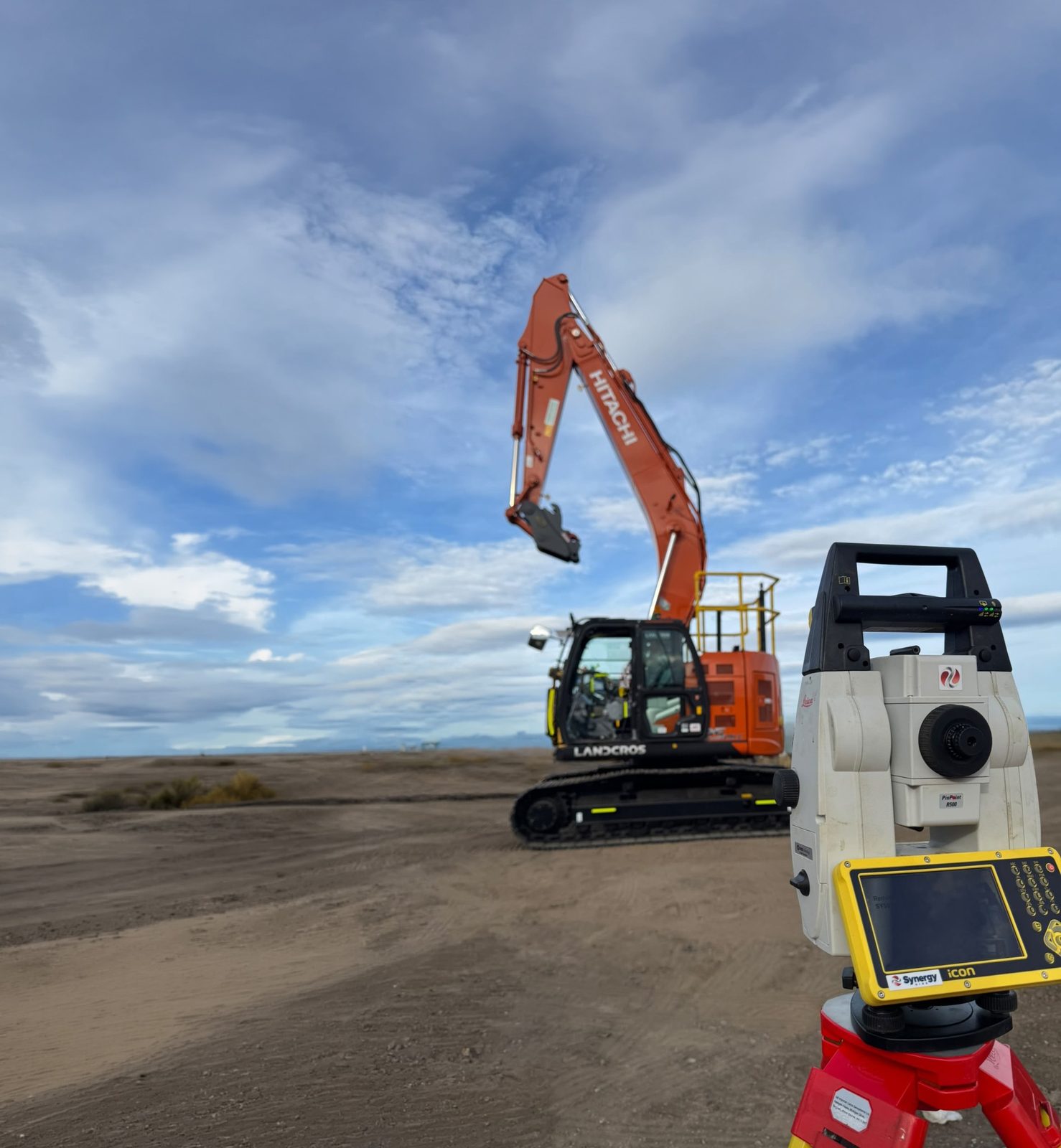 Leica total station beside a Hitachi excavator on site